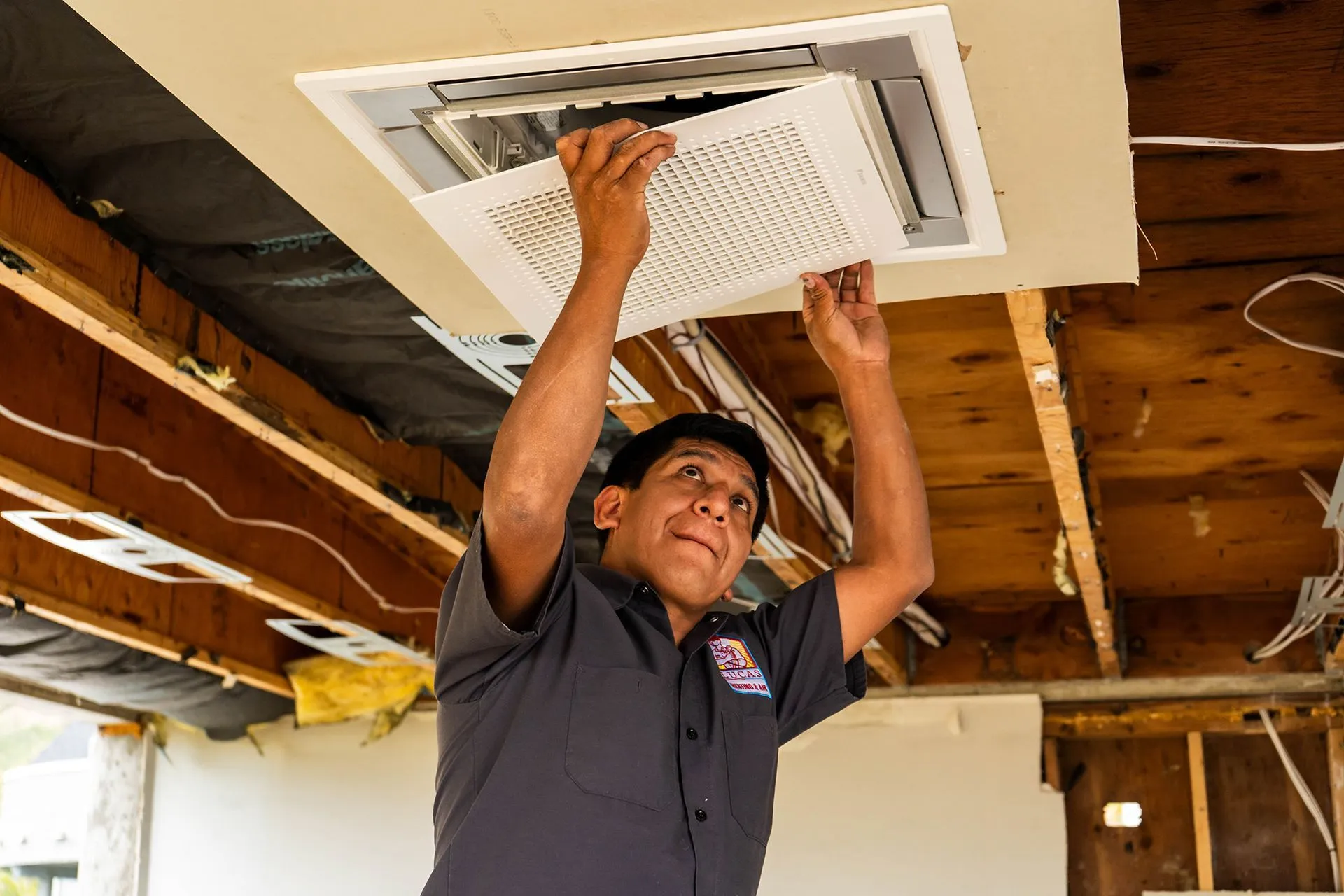 Lucas Heating and Air technician installing a flush ceiling-mounted air unit
