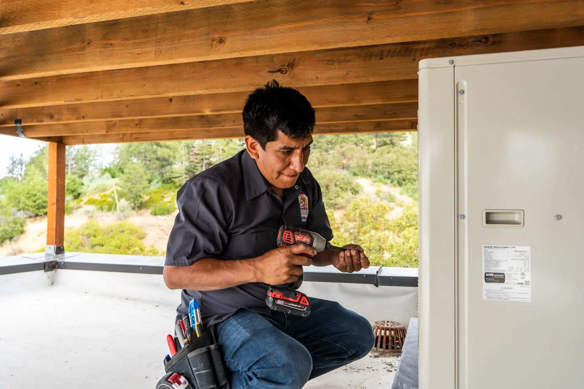 Lucas Heating and Air technician fastening a new outdoor HVAC unit with a drill