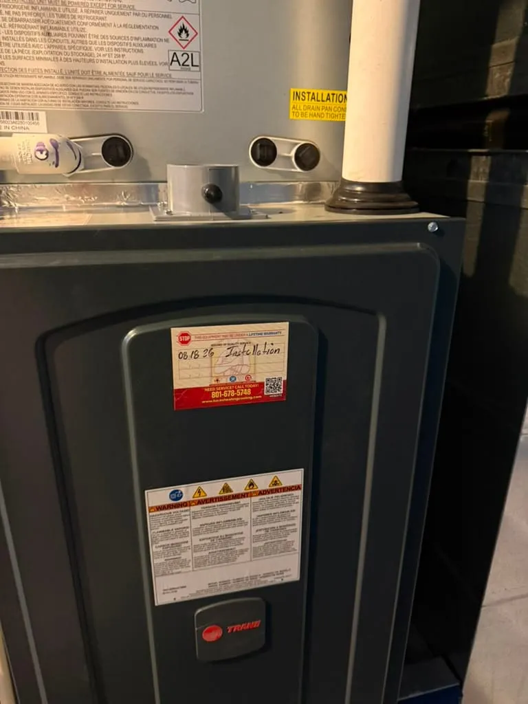 High-efficiency Trane furnace and coil installed by Lucas Heating and Air in Woods Cross, with the company's dated installation record sticker on the cabinet